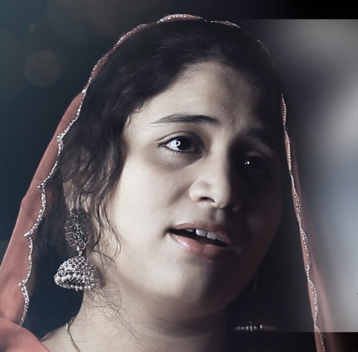 Sabiha singing, wearing a rust-colored dupatta and jhumka earrings